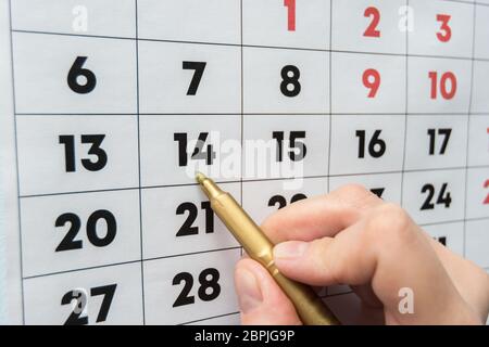Marcatore a mano indica la data sul calendario da parete Foto Stock