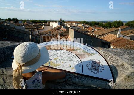 Una ragazza giovane con cappello di fronte alla mappa di orientamento su un muro di pietra si affaccia sulla città di Arles.Bouches-du-rhone.Alpes-Cote d'Azur.France Foto Stock