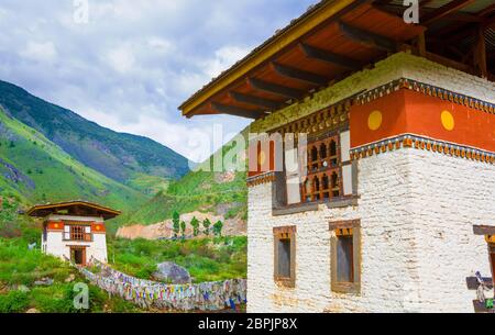 Vista laterale del ponte sospeso a piedi con molte bandiere di preghiera colorate in Bhutan, tutte le parole di script mantra sull'edificio sono utilizzati per promuovere Foto Stock