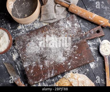 Pane bianco di farina di frumento, legno mattarello e la vecchia scheda di taglio su una tavola nera, vista dall'alto Foto Stock