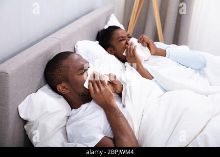 Africani malati Coppia Giovane sdraiato sul letto soffia il naso in camera da letto Foto Stock