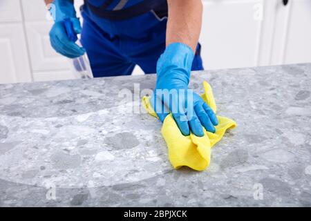 La sezione centrale di un maschio bidello sporca la pulizia della cucina con la bottiglia spray e igienico Foto Stock