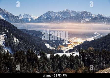 Dobbiaco al tramonto con nuvole e montagne innevate. Italia Foto Stock