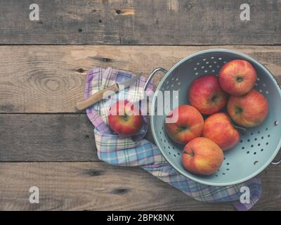 Deliziose mele biologiche in un vecchio usato scolapasta su una tavola in legno rustico, tono di piatti in stile vintage con vista da sopra Foto Stock