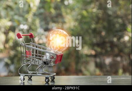 Lampadina a risparmio energetico con carrello spesa concetto finanziario e shopping e spazio di copia per inserire testo. Foto Stock