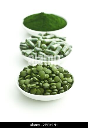 Verde chlorella pillole o orzo verde pillole e la polvere in un recipiente isolato su sfondo bianco. Foto Stock