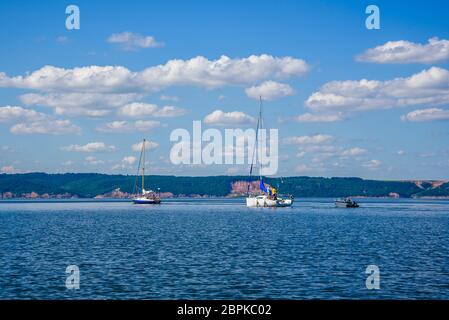 Due barche a vela e barche a motore sul fiume. Foto Stock