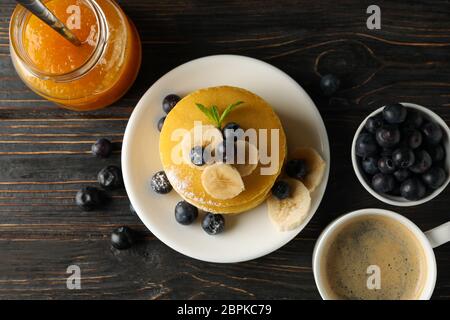 Marmellata, caffè, frittelle con mirtillo e banana su sfondo di legno Foto Stock