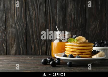 Composizione con frittelle, banana, mirtillo e marmellata su sfondo di legno Foto Stock