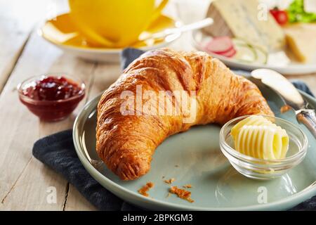 Tutto croccante e croissant fresco servito sulla piastra in ceramica con riccioli di burro in ciotole in vetro. Ristorante tavola in close-up Foto Stock