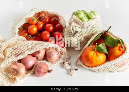 Fresche biologiche generi alimentari di frutta e verdura confezionati in eco-friendly riutilizzabile sacchetti netto, visto in close-up su sfondo bianco Foto Stock