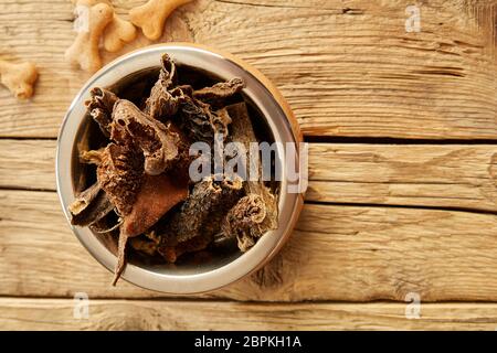 Ciotola di grezzo materie trippa o le frattaglie per un cane visto dall'alto verso il basso su un rustico pavimento in legno con spazio di copia Foto Stock