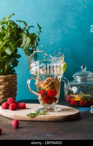 tè alla menta con lampone su tavola di legno con spruzzi Foto Stock