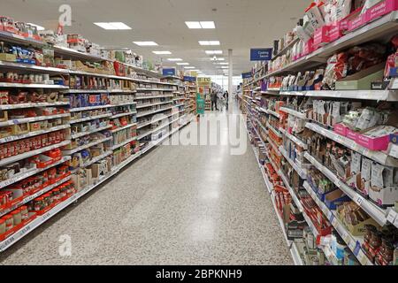 Persone acquirenti al supermercato Tesco Extra negozio interno corsia per lo shopping & scaffali alimentari impilati Pickles cottura Sauces riso secco Inghilterra Regno Unito Foto Stock