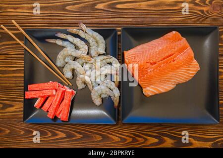 Filetti di pesce rosso, gamberi e bastoni di granchio su sfondo di legno Foto Stock