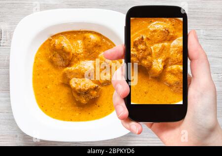Concetto di viaggio - visitatore fotografie di cucina indiana di Murg Makhan Masala barbequed pezzi di pollo in pomodoro piccante e cremosa salsa di curry su smartp Foto Stock