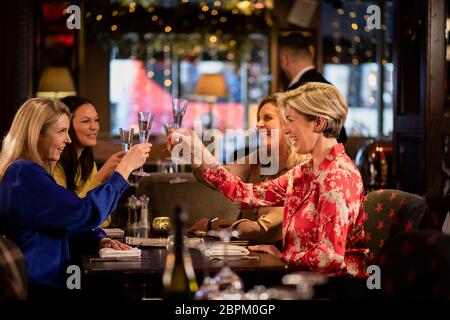 Piccolo gruppo di femmina matura amici facendo un brindisi celebrativo seduti attorno a un tavolo in un ristorante. Foto Stock