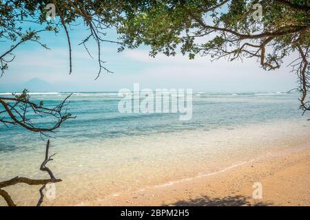 Una spiaggia tropicale con acque cristalline in una cornice di alberi e il vulcano di Bali in background, Gili Trawangan, Indonesia, 25 aprile 2018 Foto Stock