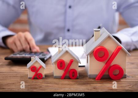 Close-up di una casa per i modelli con simbolo di percentuale di fronte ai mediatori che lavorano in ufficio Foto Stock