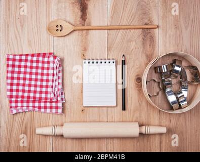 Vuoto notebook aperti in linea e cucina in legno accessori, concetto di ricetta Foto Stock