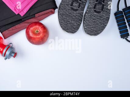 Tessuto nero scarpe e altri elementi per il fitness su uno sfondo bianco, vista dall'alto Foto Stock