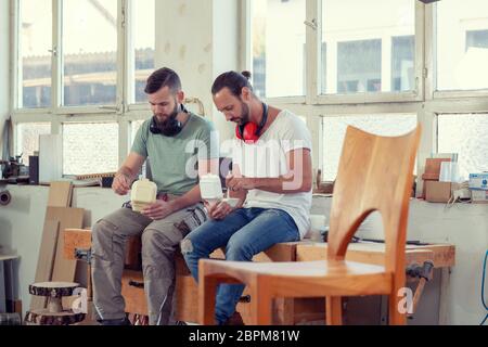 due uomini in abbigliamento da lavoro in un laboratorio di falegname che si rompono Foto Stock