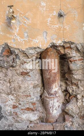 Vecchia grondaia all'interno del muro rotto dalle intemperie. Ideale per i concetti. Foto Stock