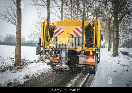 Servizio invernale carrello spandimento di sale e sabbia sulla superficie della strada per impedire la formazione di ghiaccio Foto Stock