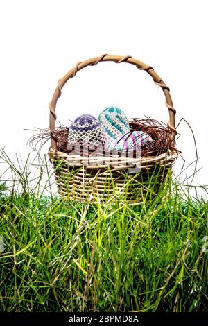 Colorate le uova di pasqua nel nido sul cestello in legno a erba verde su sfondo bianco. Buona Pasqua Foto Stock