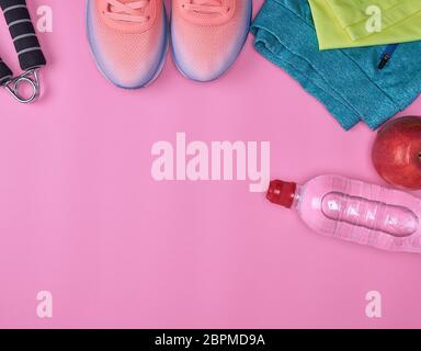 Sport calzature di materie tessili e altri elementi per il fitness su uno sfondo rosa, vista dall'alto Foto Stock