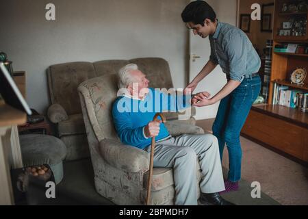 Ragazzo adolescente sta aiutando il suo nonno al di fuori della sua poltrona. Foto Stock