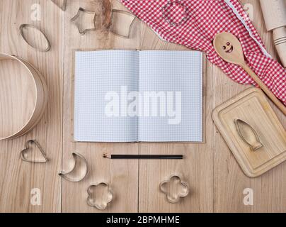 Vuoto notebook aperti in linea e cucina in legno accessori, concetto di ricetta Foto Stock