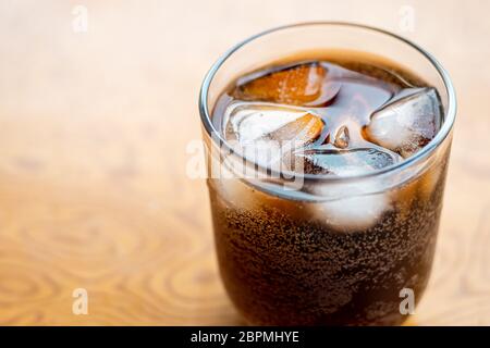 Primo piano vetro riempito con bevanda analcolica di cola gassata con cubetti di ghiaccio. Fuoco selettivo Foto Stock