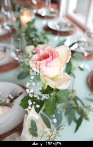 Bella rosa su tavolo festivo con breve profondità di campo per una cena di nozze Foto Stock