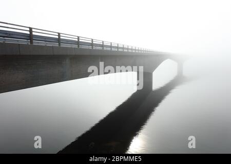 Ponte di cemento sul mare in mezzo ad una nebbia profonda Foto Stock