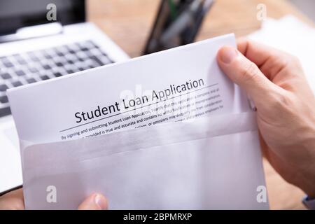 Close-up di mano di una persona la rimozione di Prestito studente Modulo di richiesta dalla busta bianca Foto Stock