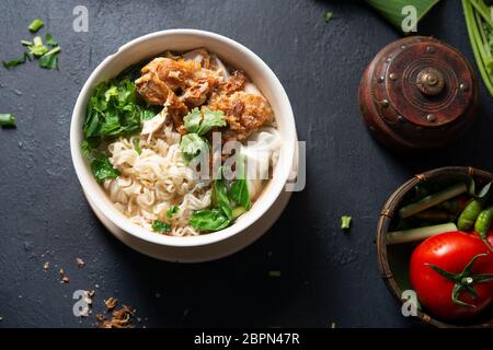 Asian spaghetti ramen zuppa con le verdure e il pollo in un recipiente su sfondo di legno. Vista superiore piatta. laici Foto Stock