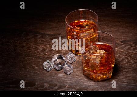 Due bicchieri di whisky con ices si erige su uno sfondo scuro Foto Stock