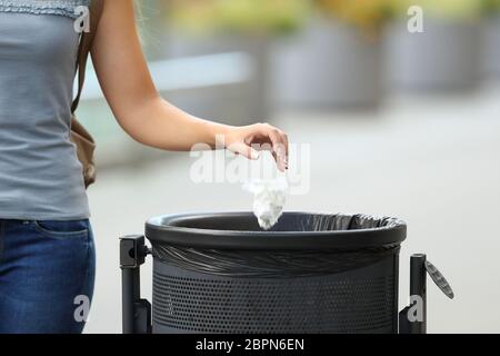 Primo piano di una mano civica donna gettando spazzatura in un cestino sulla strada Foto Stock