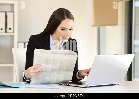Imprenditrice concentrato di lavoro un confronto quotidiano con i contenuti online in un computer portatile su una scrivania in ufficio Foto Stock