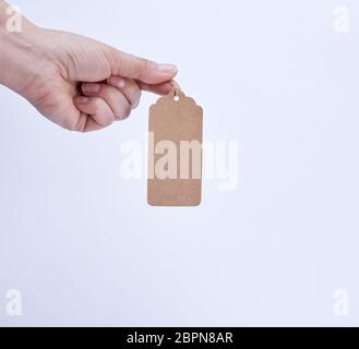 Femmina tenuta a mano una carta marrone tag vuoto su una fune, sfondo bianco Foto Stock