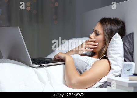 Preoccupato di trovare una donna cattiva notizia in un computer portatile sul letto nella notte a casa Foto Stock
