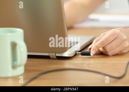 Close up donna mani collegando il caricabatterie in un computer portatile Foto Stock