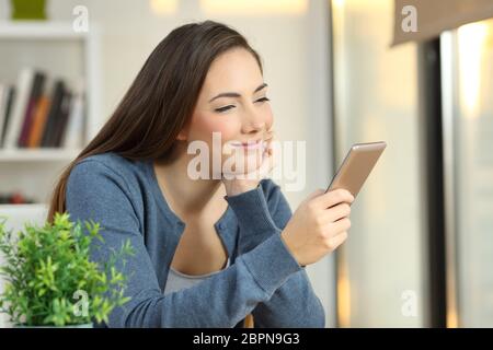 Ritratto di una ragazza rilassato controllando uno smart phone a casa Foto Stock