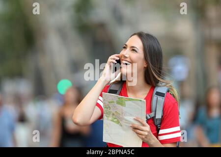 Felice teen vocazione turistica sul telefono per la strada e guardando al di sopra Foto Stock