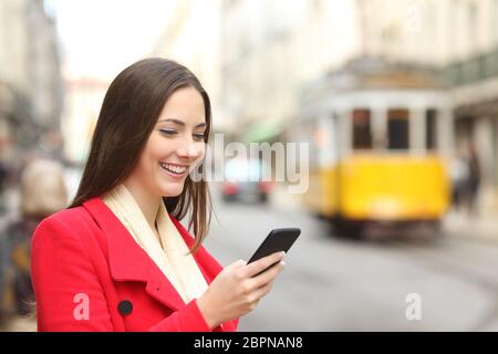 Donna felice in rosso con uno smart phone in una città vecchia Foto Stock
