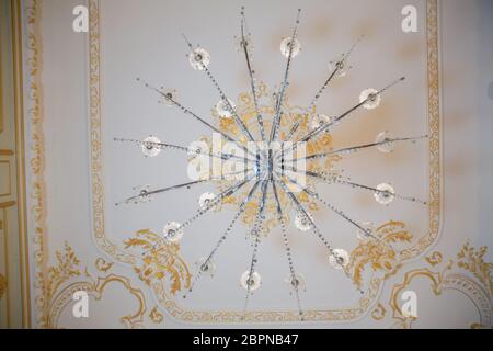 Lampadario in cristallo con luci incandescenti fotografate dal basso. Una vista dal basso su un ricco lampadario appeso ad un soffitto. Lampadario di cristallo Foto Stock