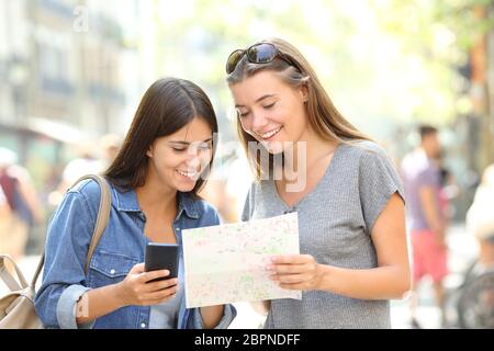 Due felici turisti in viaggio consulting uno smart phone e una guida della carta in strada Foto Stock