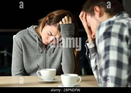 Una triste coppia di adolescenti si lamenta di stare seduti in un bar la notte Foto Stock