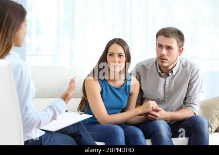 Preoccupato per il giovane ascoltando il matrimonio consigliere durante una terapia seduto su un divano a casa Foto Stock